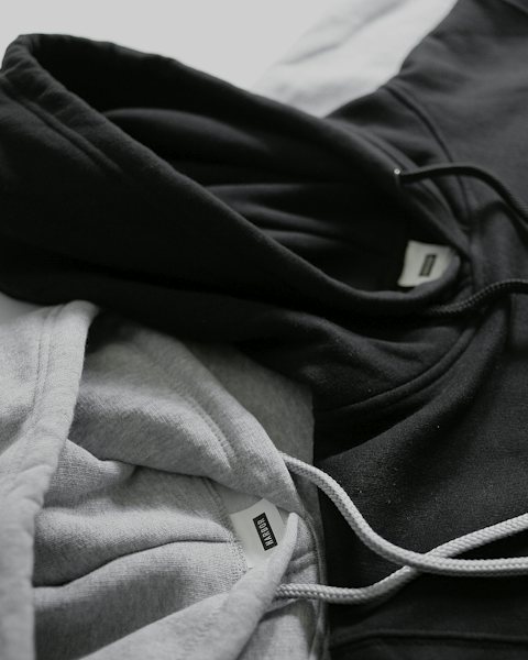 Black and ash gray hoodies folded, drawcords visible