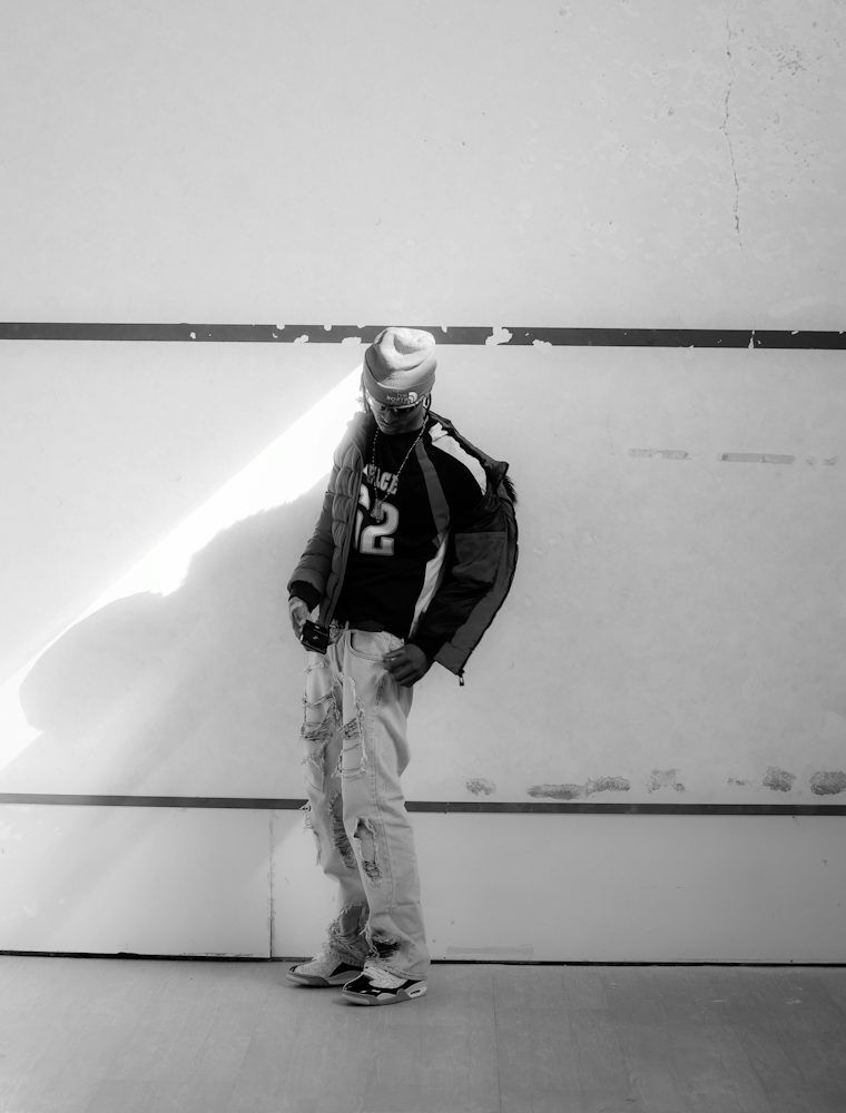 Model in a cap and padded jacket against a white wall with a painted stripe