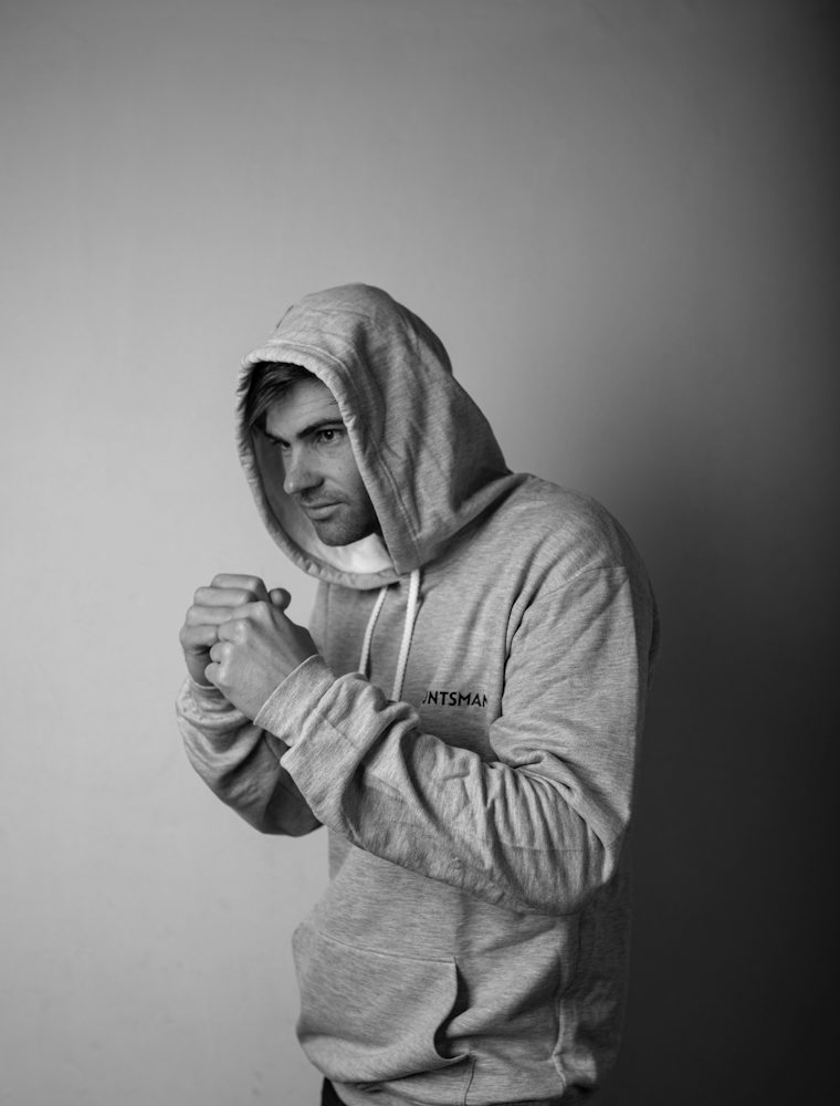 Model in a gray hoodie raising fists in a boxing stance