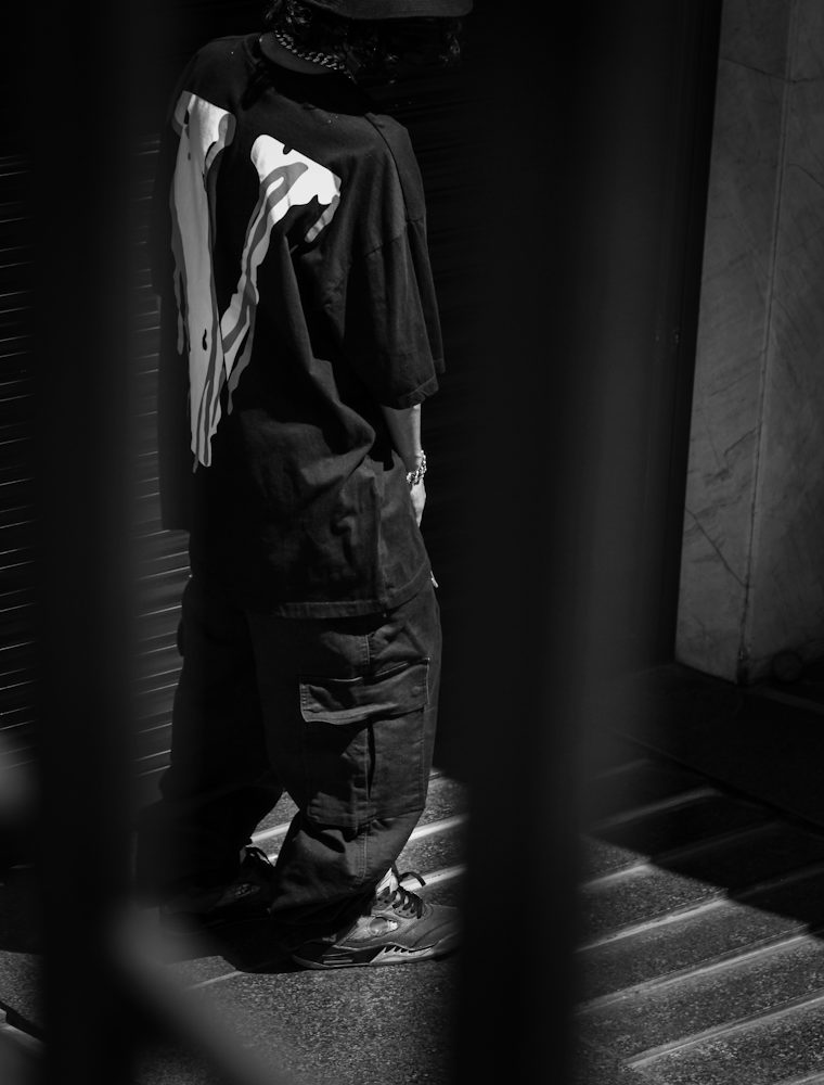 Model in a bucket hat and wide cargo trousers in a dark stairwell