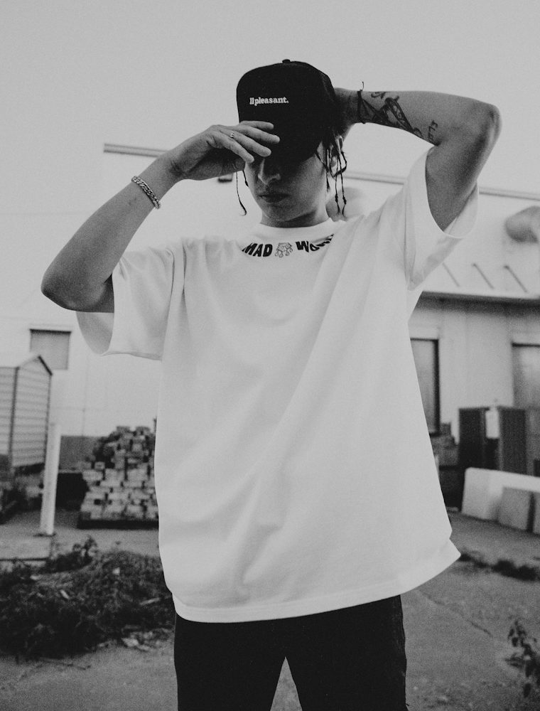 Model in an oversized white t-shirt adjusting a black cap