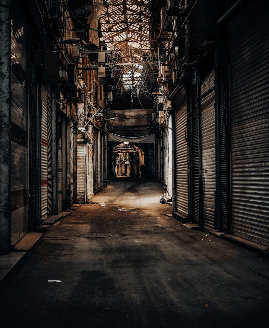 Narrow city alley at night lined with closed metal shutters